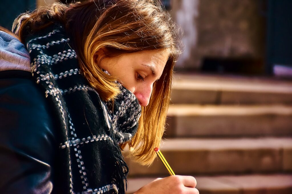 Woman with scarf drawing with a pencil outdoors