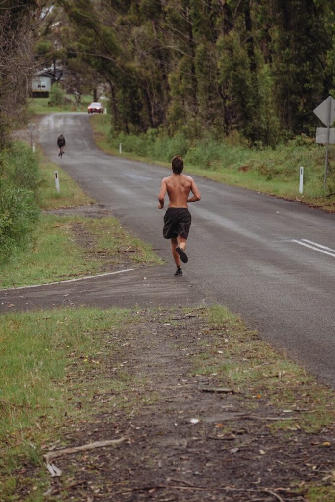 man in brown shirt running on gray asphalt road during daytime